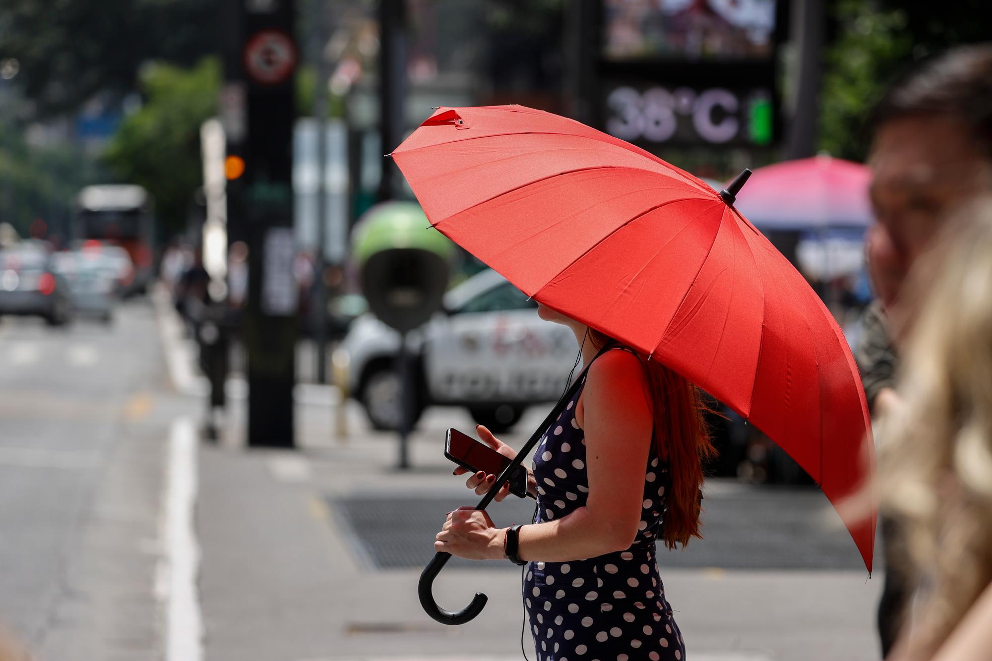 epa10975082 A woman protects herself from the sun with an umbrella on Paulista Avenue, where urban thermometers register a temperature of 38.0 degrees Celsius in the city of Sao Paulo, Brazil, 14 November 2023. Eight heat waves have been recorded in Brazil so far this year, something that meteorologists attribute to the climate crisis and the El Nino phenomenon. EPA/Sebastiao Moreira
