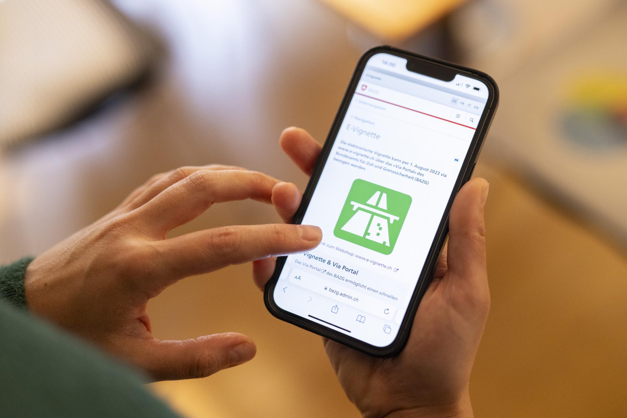 Eine Frau loest eine elektronische Vignette, die E-Vignette, zur Nutzung von abgabepflichtigen Autobahnen und Autostrassen fuer das Jahr 2024 auf ihrem Telefon, aufgenommen am Freitag, 1. Dezember 2023 in Zuerich. (KEYSTONE/Ennio Leanza)