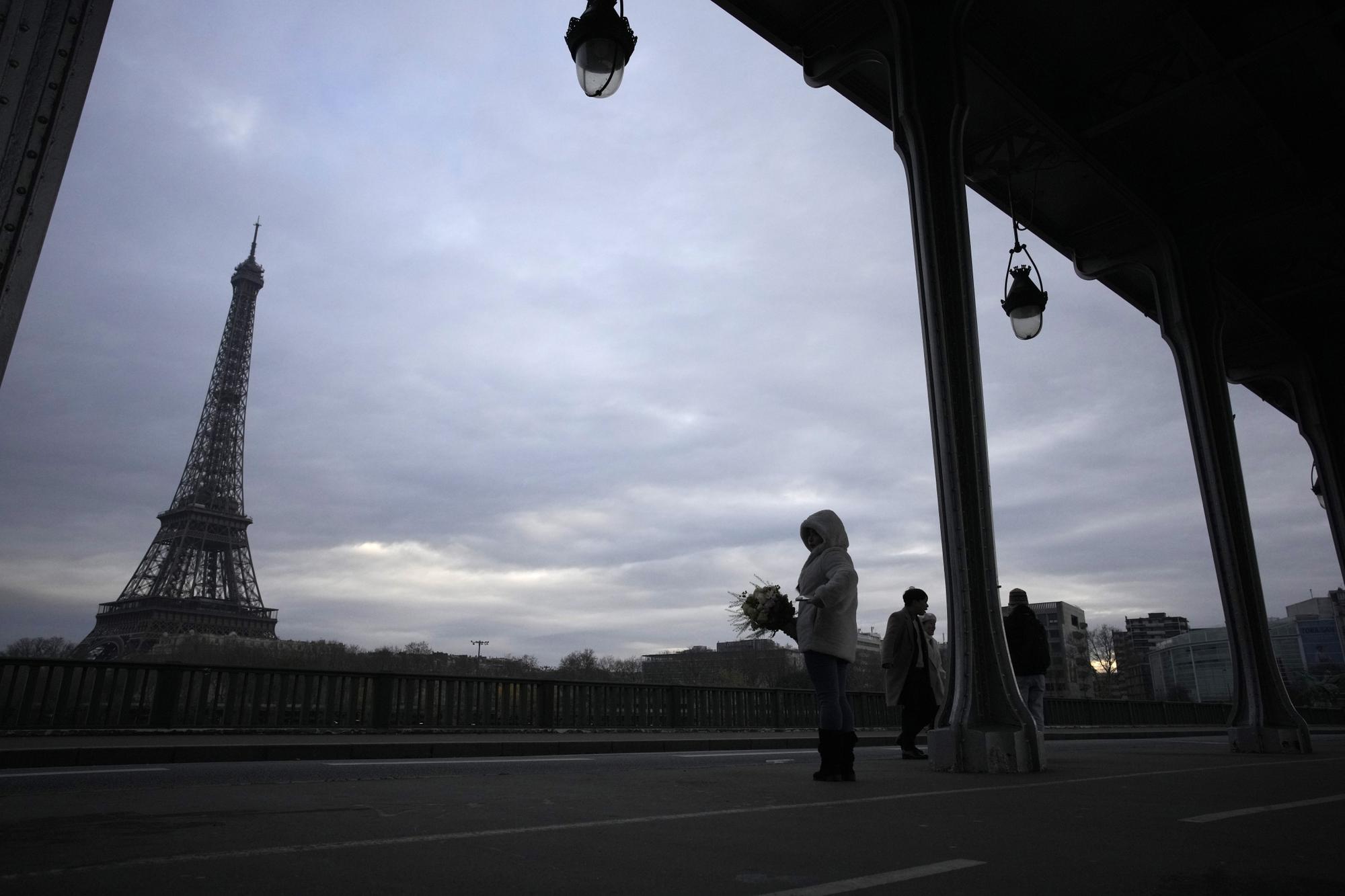 Tourists stand on the scene where a man targeted passersbys late saturday, killing a German tourist with a knife and injuring two others in Paris, Sunday, Dec. 3, 2023. Police subdued the man, a 25-year-old French citizen who had spent four years in prison for a violent offense. After his arrest, he expressed anguish about Muslims dying, notably in the Palestinian territories. (AP Photo/Christophe Ena)