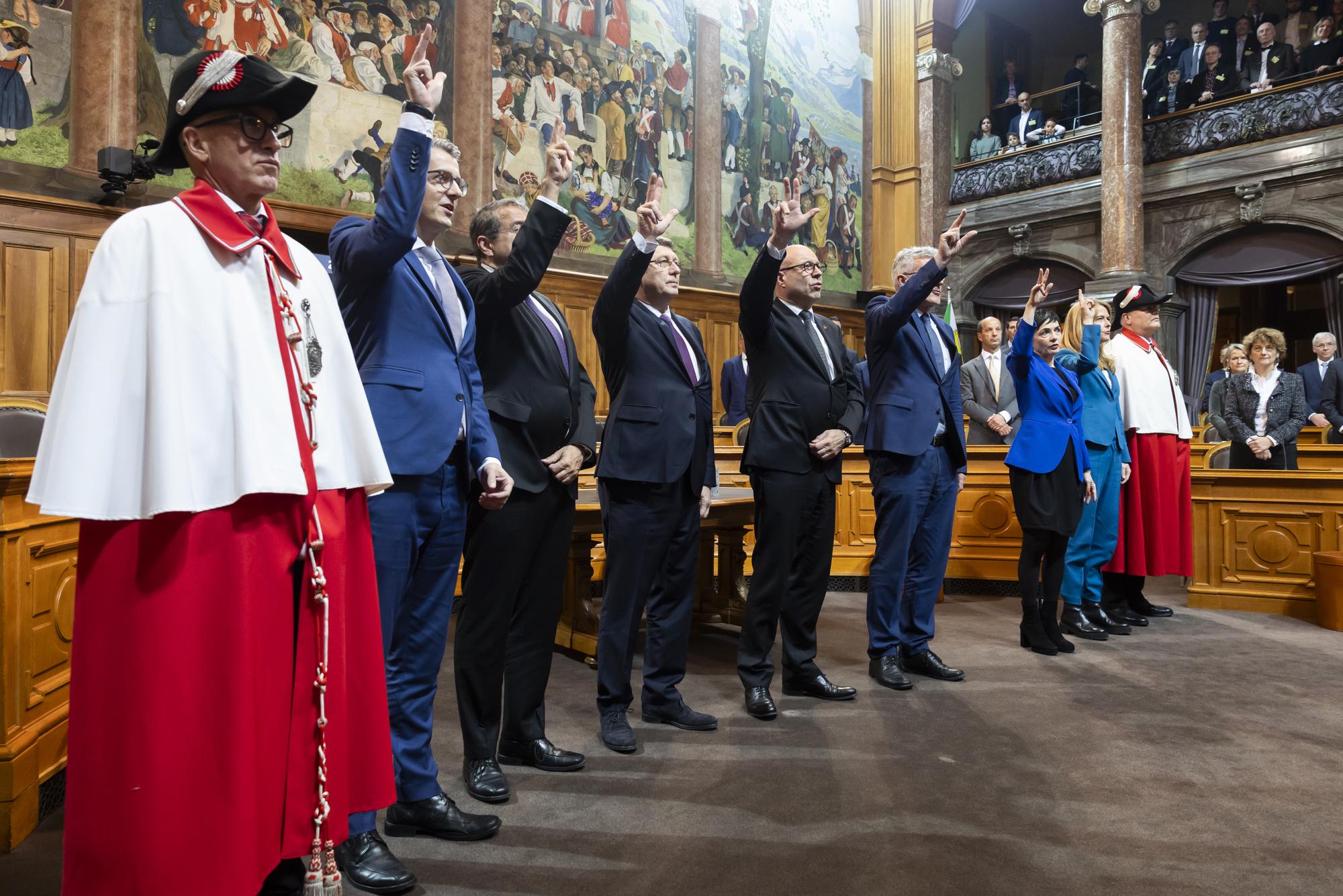 Die neuen Staenderaete Benjamin Muehlemann, FDP-GL, Pascal Broulis, FDP-VD, Mauro Poggia, MCG-GE, Fabio Regazzi, Mitte-TI, Pirmin Schwander, SVP-SZ, Marianne Binder-Keller, Mitte-AG und Petra Goessi, FDP-SZ, von links, flankiert von den Weibeln Peter Truffer, links, und Charly Riesen, schwoeren den Eid bei der Vereidigung waehrend der ersten Sitzung zu Beginn der 52. Legislatur am ersten Tag der Wintersession der Eidgenoessischen Raete, am Montag, 4. Dezember 2023, im Staenderat in Bern. (KEYSTONE/Peter Klaunzer)