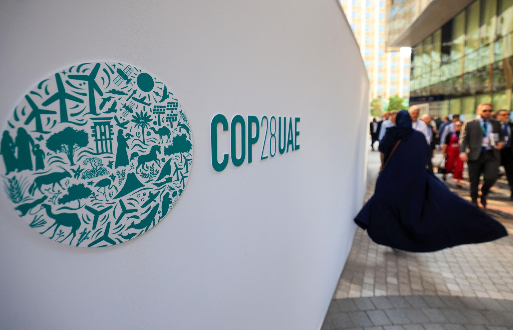 People walk past a COP28 sign at the Expo City during the United Nations climate summit in Dubai on December 5, 2023. (Photo by Karim SAHIB / AFP)