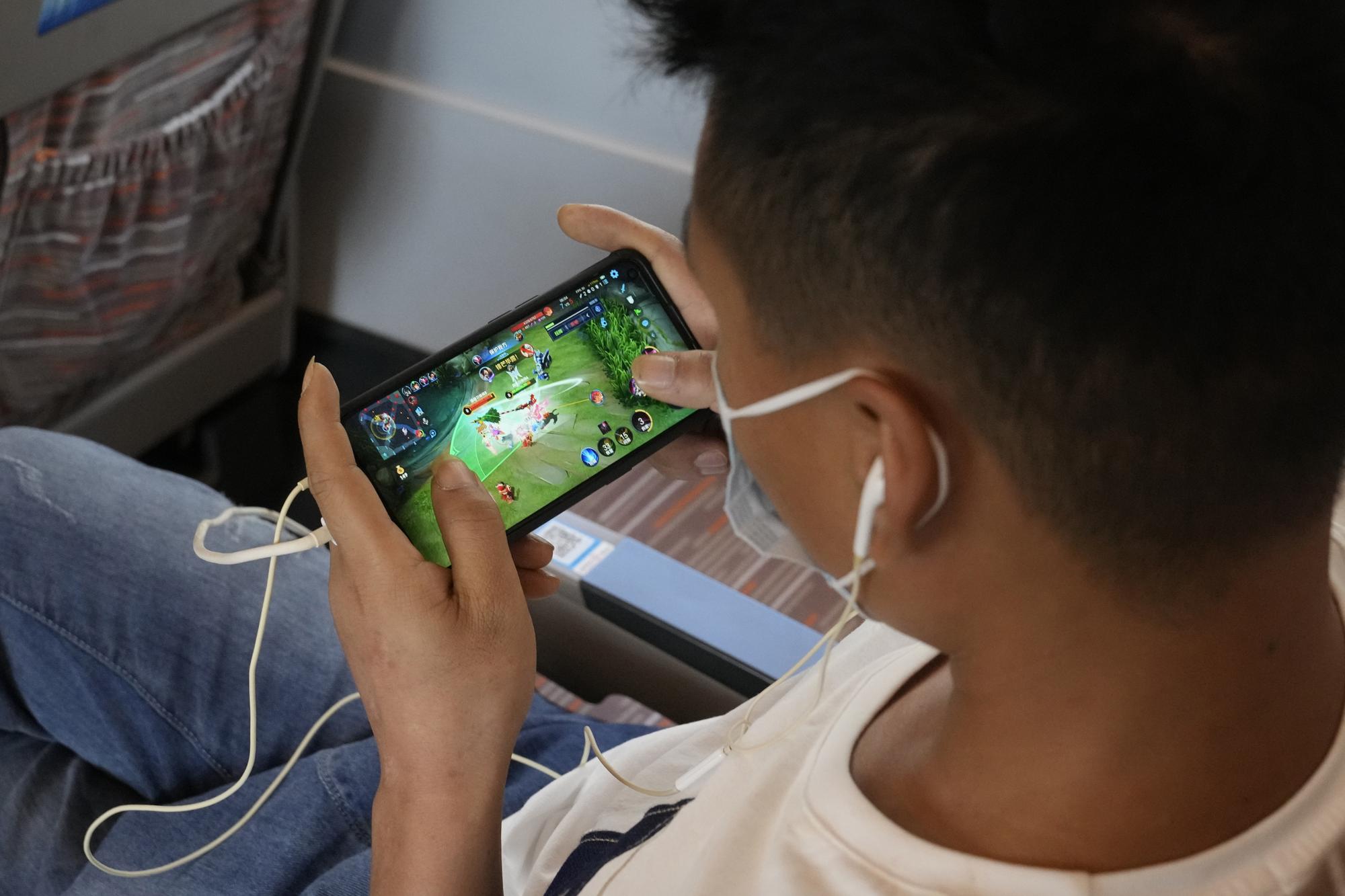 Un homme joue à un jeu en ligne de la plateforme de jeux chinoise Tencent dans un train reliant Henan à Pékin, mercredi 15 septembre 2021.