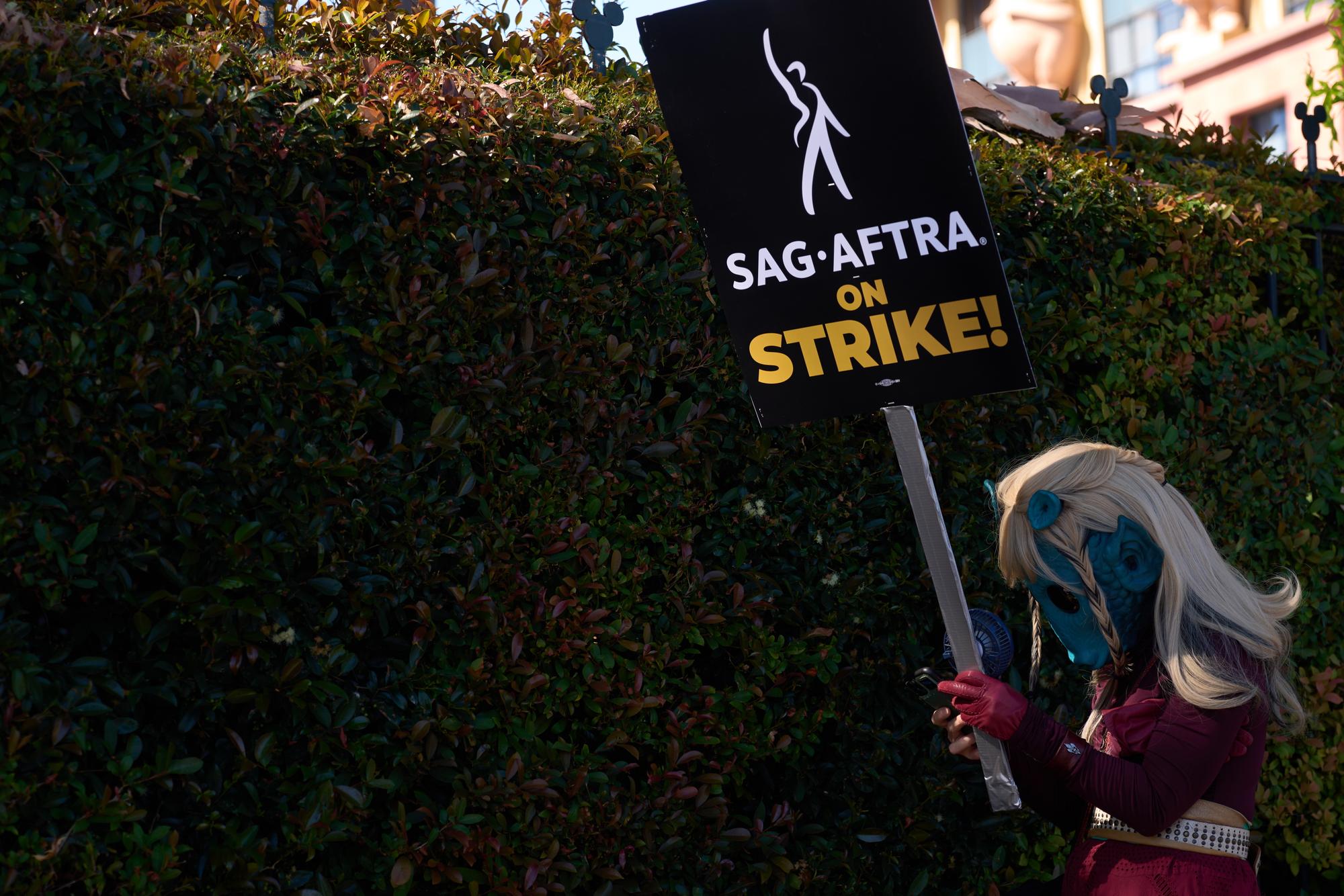 epa10746728 A person dressed as a Disney Avatar character fans themself to stay cool during a demonstration with members of SAG-AFTRA (Screen Actors Guild - American Federation of Television and Radio Artists) in front of the Walt Disney studios in Burbank, California, USA, 14 July 2023. The decision to go on strike comes after the negotiations between SAG-AFTRA and AMPTP failed as they reached their 12 July deadline at midnight. EPA/ALLISON DINNER