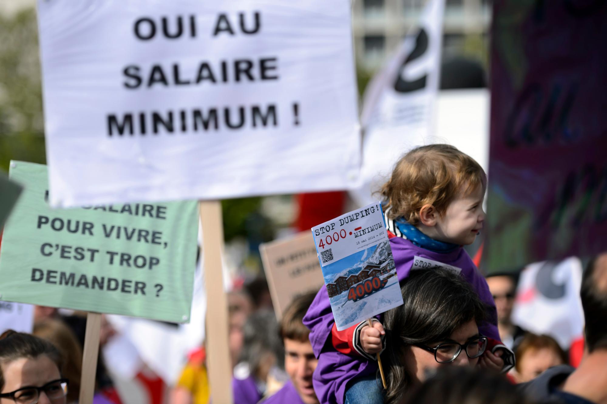 Des personnes defilent avec des banderoles pour l' initiative sur le salaire minimum a 4000frs lors de la manifestation du 1er Mai, la fete du travail, ce mercredi 1 mai 2014 dans les rues de Lausanne. (KEYSTONE/Laurent Gillieron)