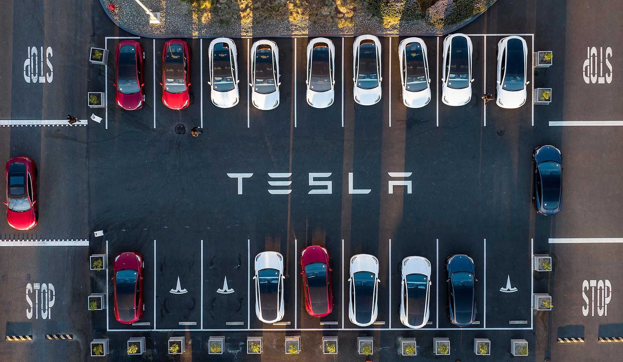 (FILES) An aerial view shows cars parked at the Tesla Fremont Factory in Fremont, California on February 10, 2022. The US transition to electric cars has hit a speed bump, with concerns about vehicle range and limited charging capacity adding to core affordability issues.  Automakers in recent weeks have pushed back EV sales targets and delayed capital projects as they seek to reduce inventories of unsold EVs at dealerships. (Photo by JOSH EDELSON / AFP)