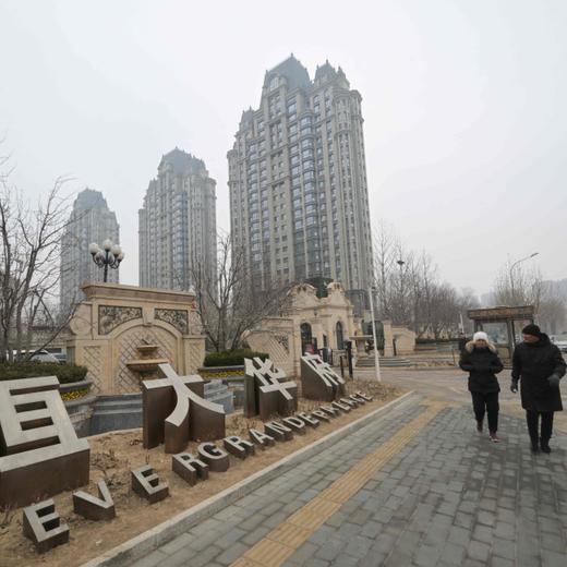 People walk past an Evergrande Group residential complex called Evergrande Palace in Beijing on January 30, 2024. A Hong Kong court on January 29 ordered the liquidation of China's property giant Evergrande, but the firm said it would continue to operate in a case that has become a symbol of the nation's deepening economic woes. (Photo by Pedro PARDO / AFP)
