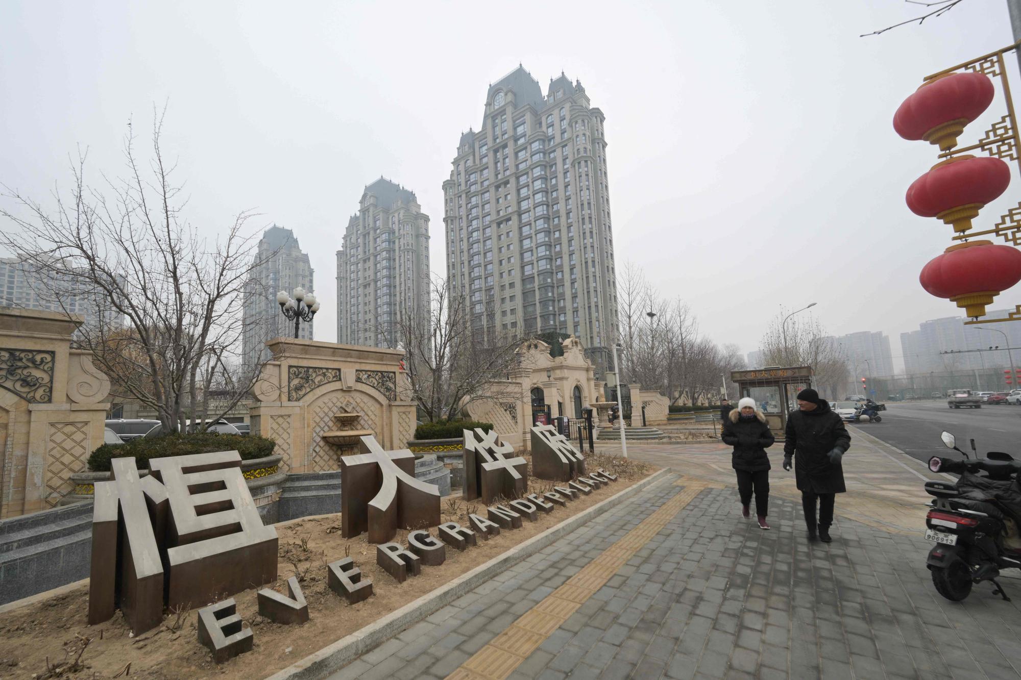 People walk past an Evergrande Group residential complex called Evergrande Palace in Beijing on January 30, 2024. A Hong Kong court on January 29 ordered the liquidation of China's property giant Evergrande, but the firm said it would continue to operate in a case that has become a symbol of the nation's deepening economic woes. (Photo by Pedro PARDO / AFP)