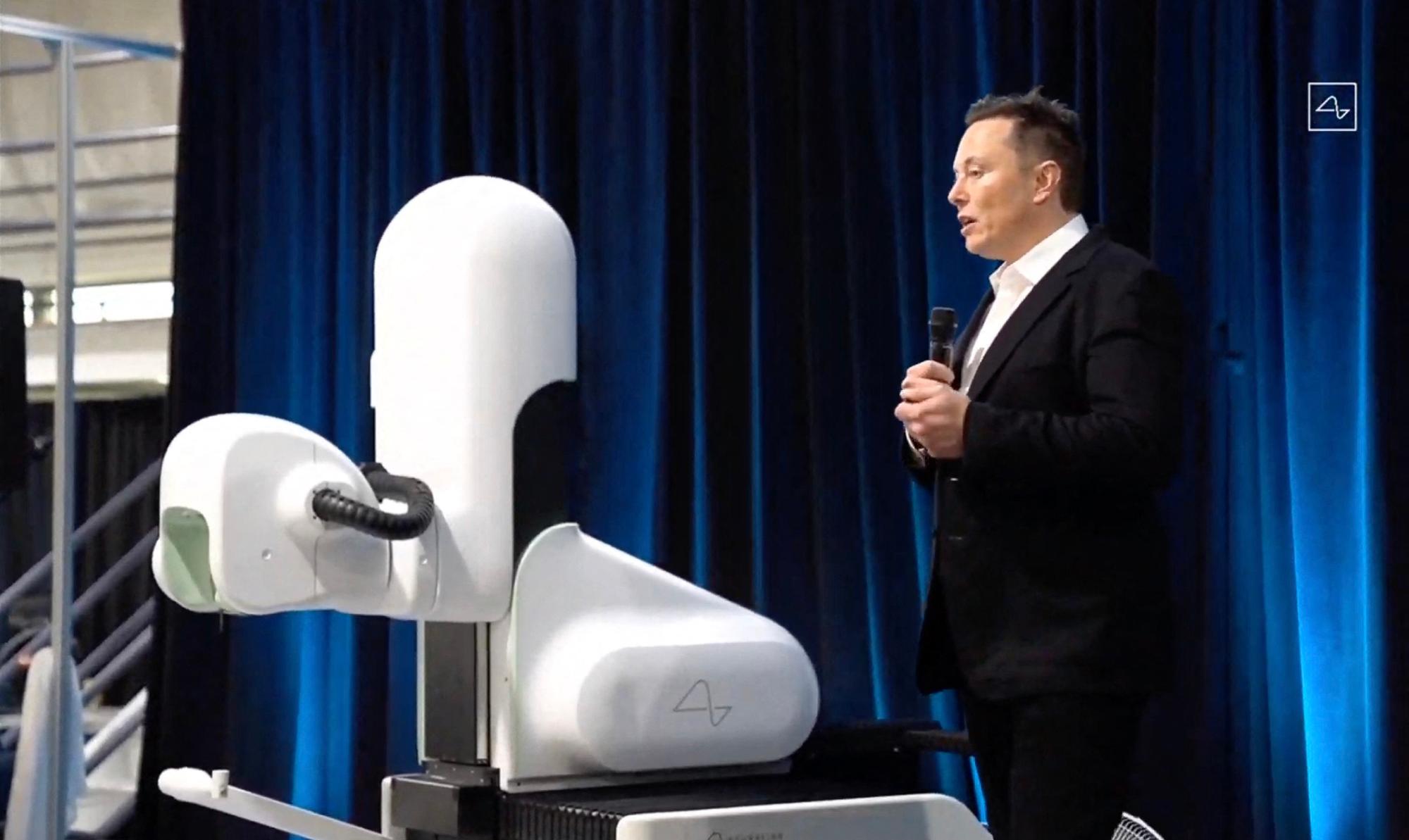This video grab made from the online Neuralink livestream shows Elon Musk standing next to the surgical robot during his Neuralink presentation on August 28, 2020. Futurist entrepreneur Elon Musk late August 28 demonstrated progress made by his Neuralink startup in meshing brains with computers, saying the work is vital to the future of humanity. (Photo by Neuralink / AFP) / RESTRICTED TO EDITORIAL USE - MANDATORY CREDIT "AFP PHOTO / NEURALINK " - NO MARKETING - NO ADVERTISING CAMPAIGNS - DISTRIBUTED AS A SERVICE TO CLIENTS