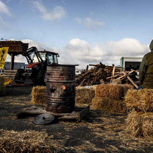 A protester sits at a blockade of the A43 highway toll during a farmers' demonstration over pay, tax and regulations, in Saint-Quentin Fallavier, near Lyon, central-eastern France, on February 2, 2024. France's agriculture minister said on February 2 that the worst of a crisis that saw farmers block roads nationwide was over, as protesters began lifting roadblocks following government promises of cash and eased regulation, and protection against unfair competition. While two main farming unions FNSEA and Jeunes agriculteurs (JA) announced the suspension of the action on February 1, urging the protesters to take their tractors off the streets, some protesters who answered the call of the Confederation Paysanne farming union said they intended to continue the movement. (Photo by JEFF PACHOUD / AFP)