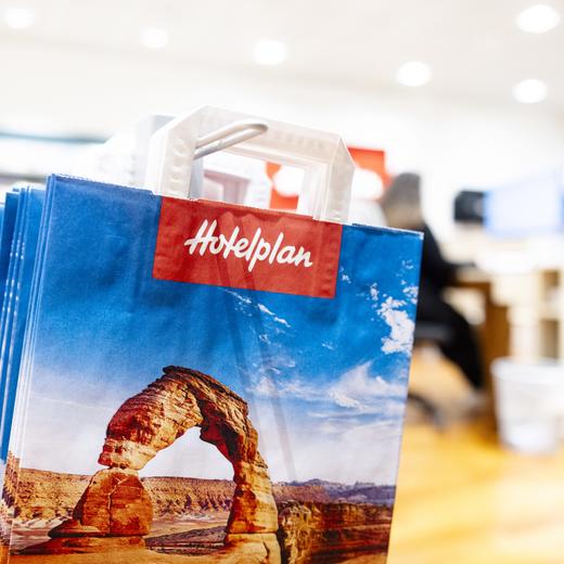 Papiersaecke mit dem Logo von Hotelplan, aufgenommen am Freitag, 2. Februar 2024 in der Filiale am Limmatplatz in Zuerich. Der Detailhandelskonzern Migros sucht neue Besitzer für die Reisetochter Hotelplan, die Kosmetik- und Hygienetochter Mibelle sowie für Melectronics und SportX. Das fuehrt zu einem grossen Stellenabbau. Die aktuelle Fokussierung werde bei der Migros Gruppe zu einem Abbau von bis zu 1500 Vollzeitstellen fuehren, heisst es in einer Mitteilung vom Freitag. (KEYSTONE/Michael Buholzer)