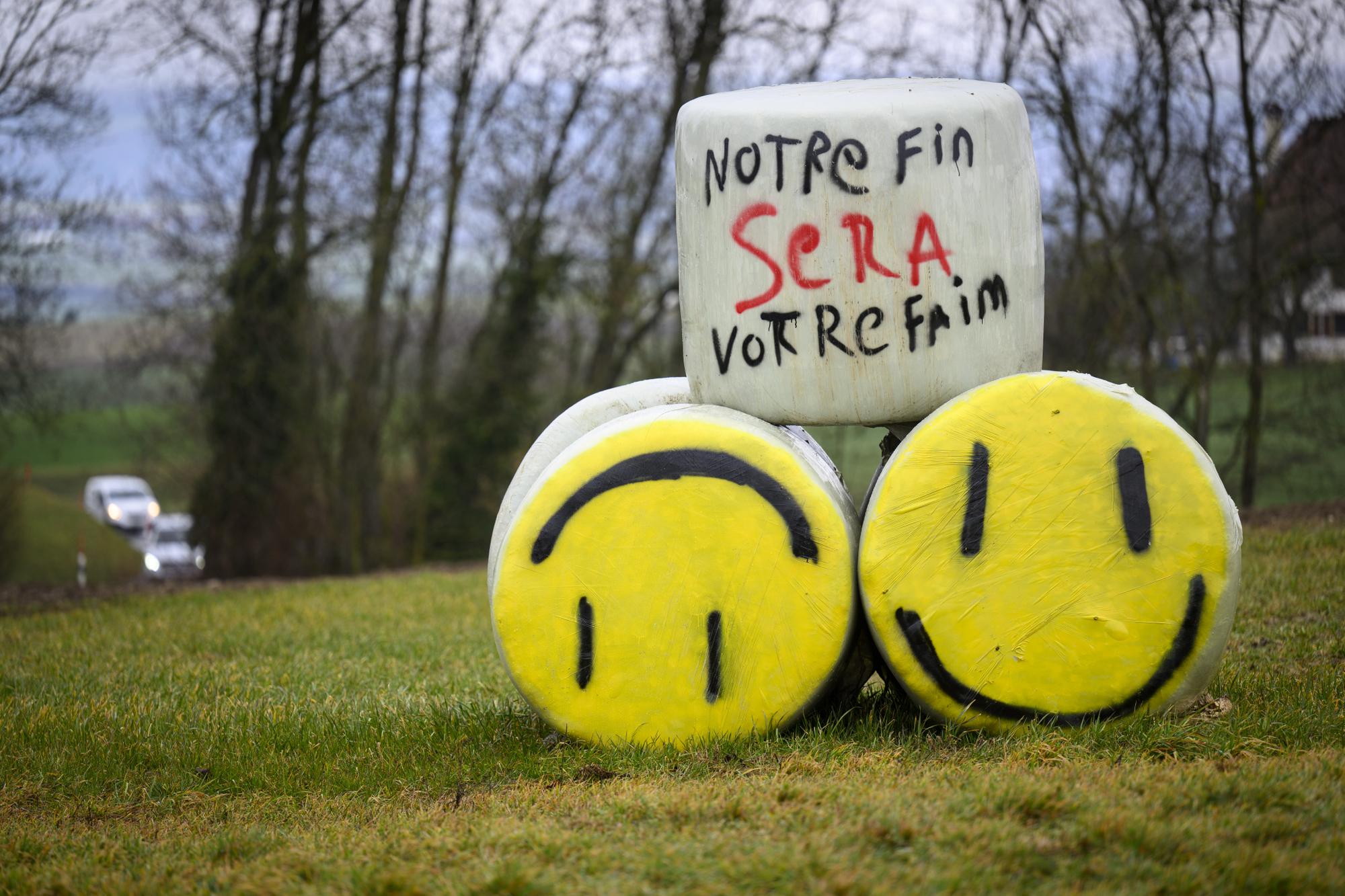 Des bottes de pailles avec un slogan "Notre fin sera votre faim" sont posees dans un champs lors d'un mouvement de protestation des agriculteurs romands au sujet des conditions dans leur secteur faisant echo aux a divers actions en France et en Allemagne, ce jeudi 8 fevrier 2024 a Bettens. (KEYSTONE/Laurent Gillieron)