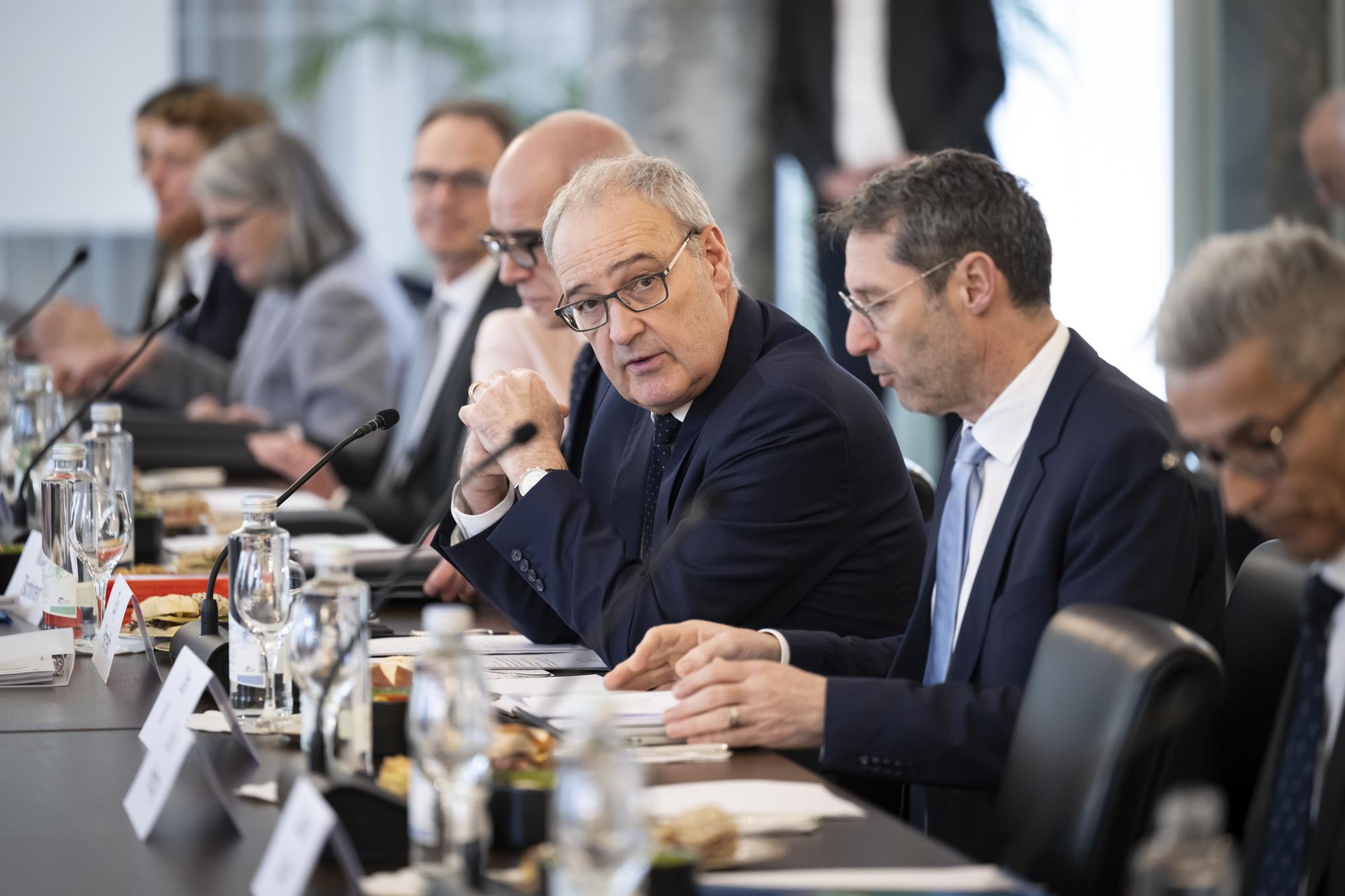 Bundesrat Guy Parmelin, Mitte, spricht zwischen Martin Tschirren, Dirktor Bundesamt fuer Wohnungswesen BWO, Mitte-links, und Urs Widmer, Kommunikationschef WBF, Mitte-rechts, im Bernerhof, kurz vor Beginn des Runden Tisches zum Thema Wohnungsknappheit zwischen Bundesrat Guy Parmelin und die Vertreterinnen und Vertreter der Kantone, Staedte und Gemeinden sowie der Bau- und Immobilienbranche, am Dienstag, 13. Februar 2024 im Bernerhof in Bern. (KEYSTONE/Anthony Anex)