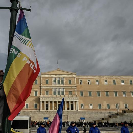 A person hangs a LGBTQ pride flag on a light pole outside the Greek Parliament during a gathering with fellow supporters of the LGBTQ community as lawmakers vote on a same-sex marriage and adoption for same-sex couples bill on February 15, 2024 in Athens. Greece's Parliament was set to legalise same-sex marriage and adoption today, a landmark reform promoted by the conservative government over the opposition of the country's powerful Orthodox Church. (Photo by Aris MESSINIS / AFP)