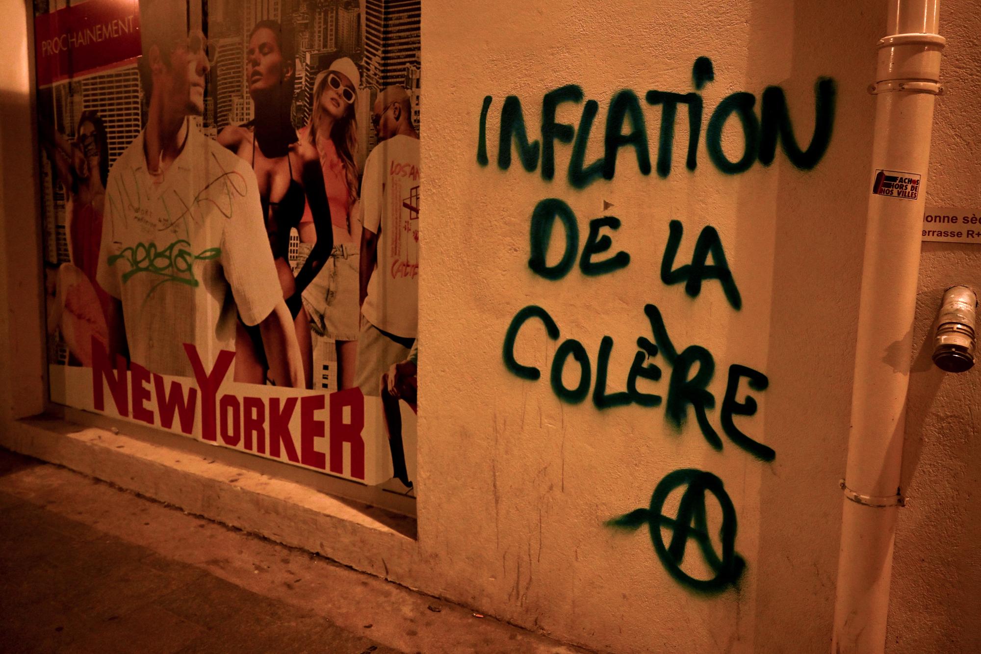 A photograph taken on March 16, 2023 shows graffiti reading "inflation of anger" during a demonstration after the French government pushed a pensions reform through parliament without a vote, using the article 49,3 of the constitution, in Marseille, southern France. The French president on March 16 rammed a controversial pension reform through parliament without a vote, deploying a rarely used constitutional power that risks inflaming protests. The move was an admission that his government lacked a majority in the National Assembly to pass the legislation to raise the retirement age from 62 to 64. (Photo by Nicolas TUCAT / AFP)