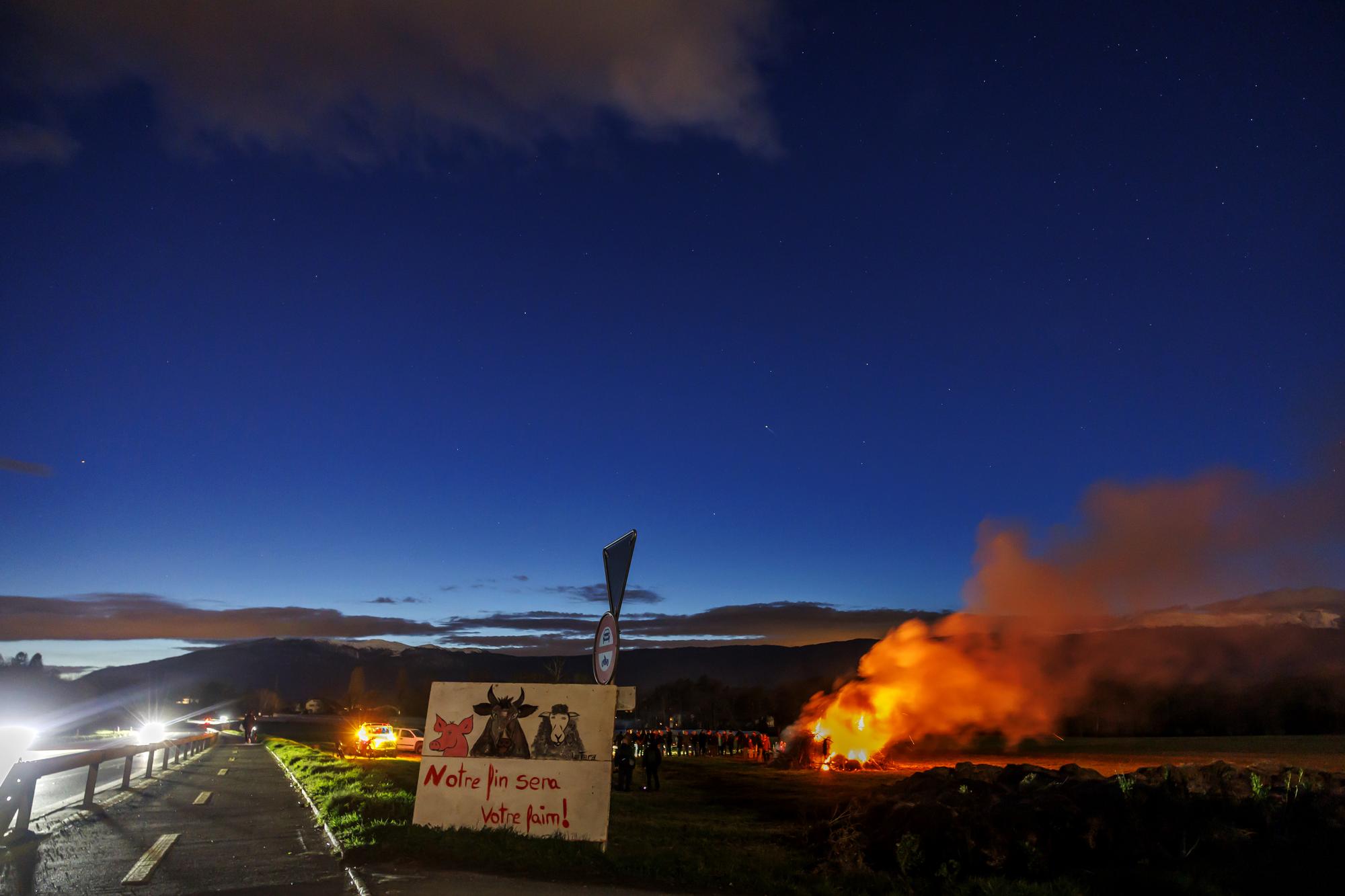 Des agriculteurs ont allume un feu sur un terrain agricole dans la campagne genevoise lors de l'action "Feu de rassemblement" a l'appel du groupe "Revolte agricole suisse", ce samedi 24 fevrier 2024 a Bernex pres de Geneve. Les agriculteurs ont allume des feux dans les champs un peu partout a travers la Suisse pour rendre visible leur mecontentement. (KEYSTONE/Salvatore Di Nolfi)