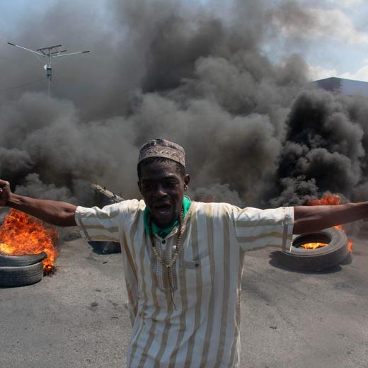 A protester reacts while tires burn in the street during a demonstration following the resignation of its Prime Minister Ariel Henry, in Port-au-Prince, Haiti, on March 12, 2024. A political transition deal in Haiti marks a key step forward for the violence-ravaged country but far more needs to be done, with some experts warning the situation could deteriorate further. (Photo by Clarens SIFFROY / AFP)